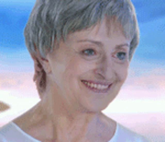 a woman with gray hair is smiling in front of a blue sky .