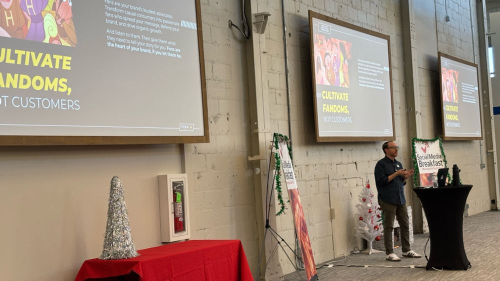 Greg standing in front of three screens showing his presentation