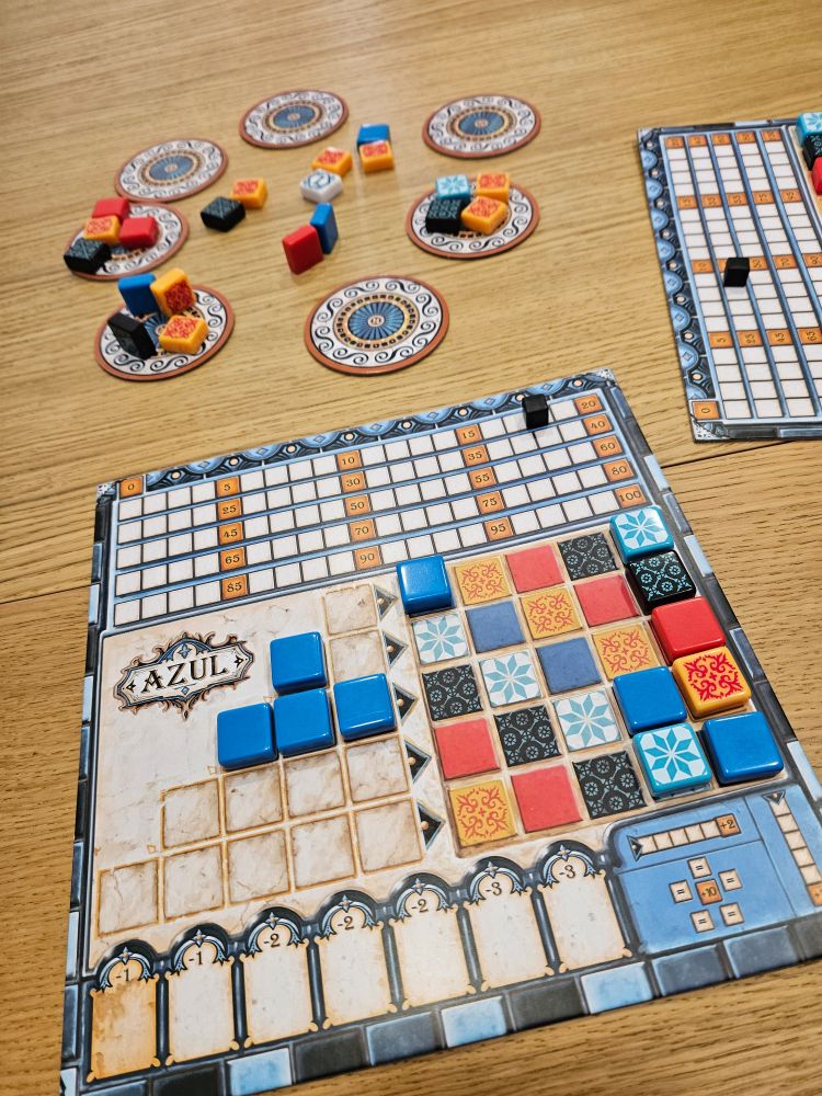 You see a board of Azul mid-game with some pieces still in the circles up for grabs