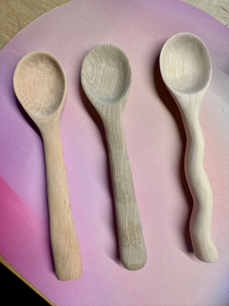 Three hand carved spoons in different styles and wood types: top down view