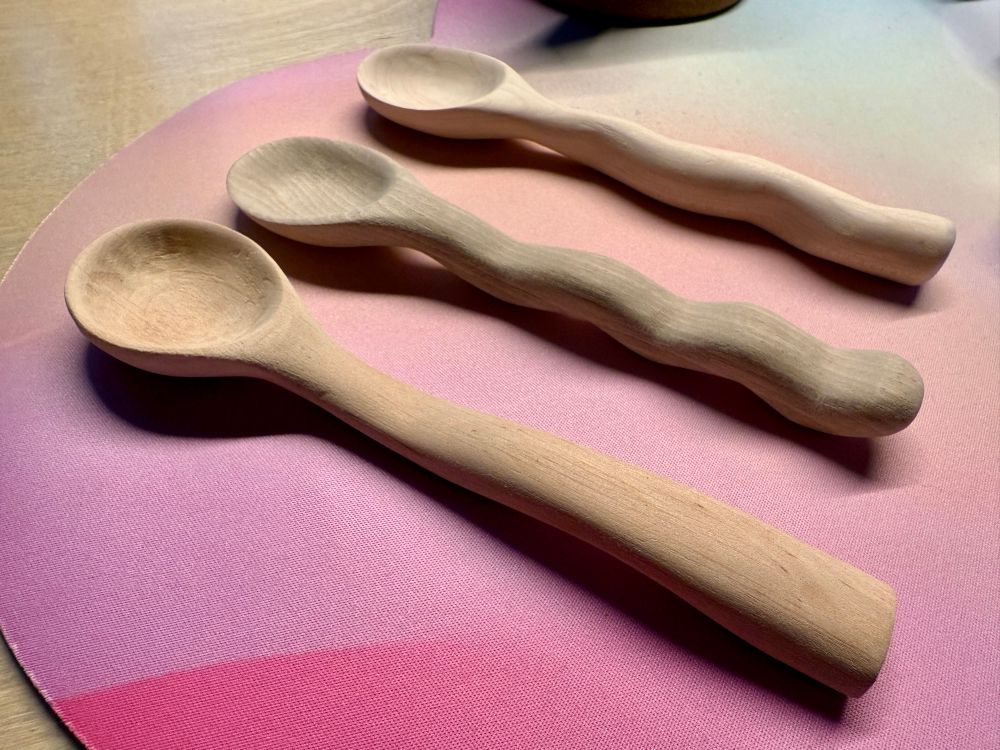 Three hand carved spoons in different styles and wood types: angled view