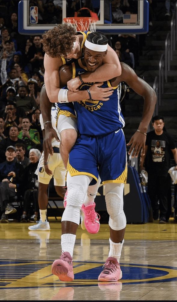 Golden State Warriors' Brandin Podziemski jumps on the back of teammate Jimmy Butler, both with big smiles after a great play during their game against the Dallas Mavericks on 2/23/25.