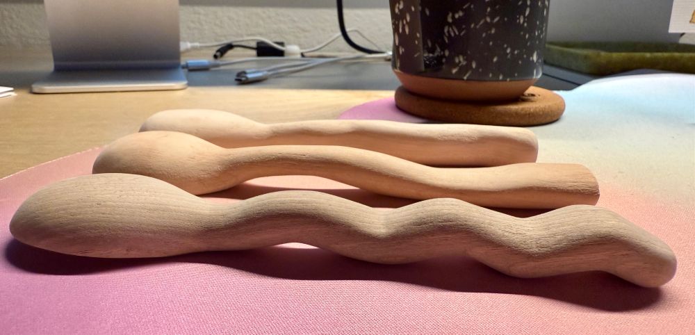 Three hand carved spoons in different styles and wood types: side view