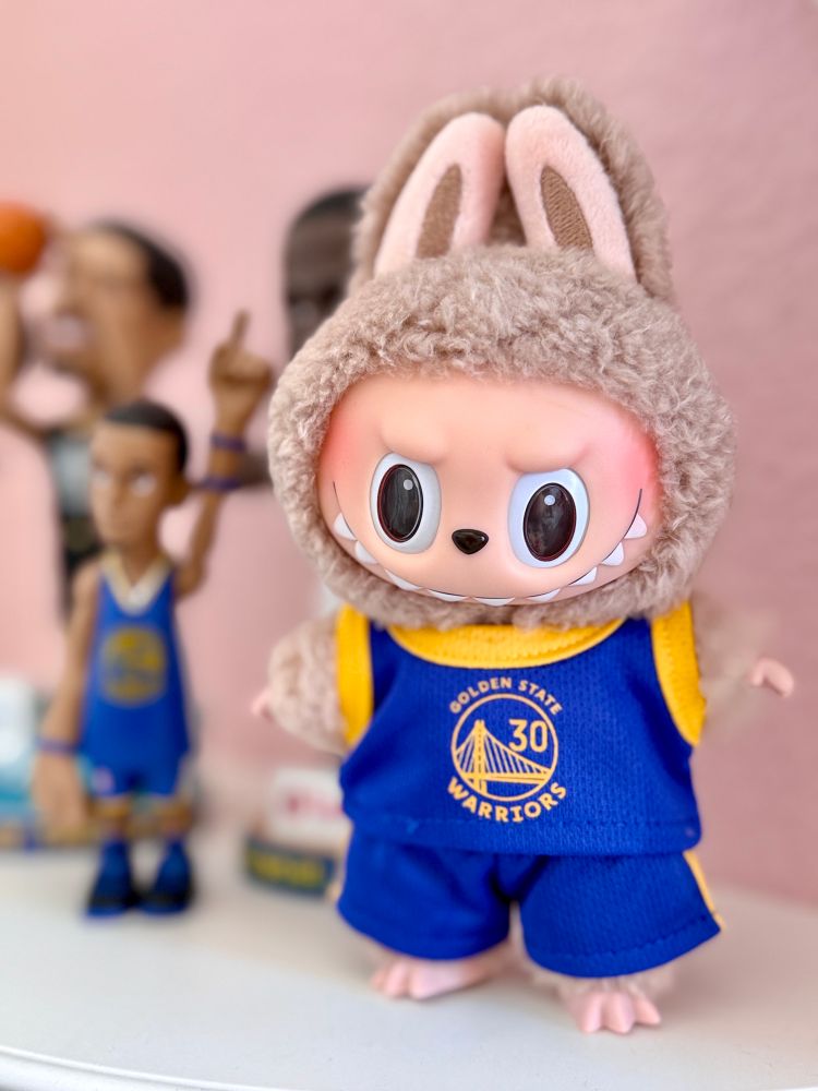 Light tan Labubu dressed in a Golden State Warriors Stephen Curry uniform. 