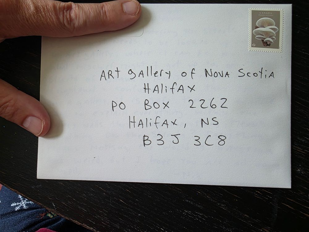 The letter with a stamp and mailing address: art gallery of Nova Scotia Halifax. Po box 2262 Halifax NS B3J 3C8. Note the mushroom stamp. Bought those two days ago. 