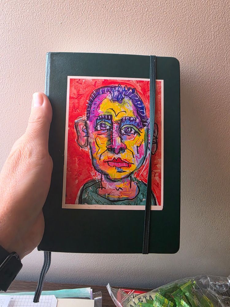 A green notebook with a sticker of one of my paintings on the front.

