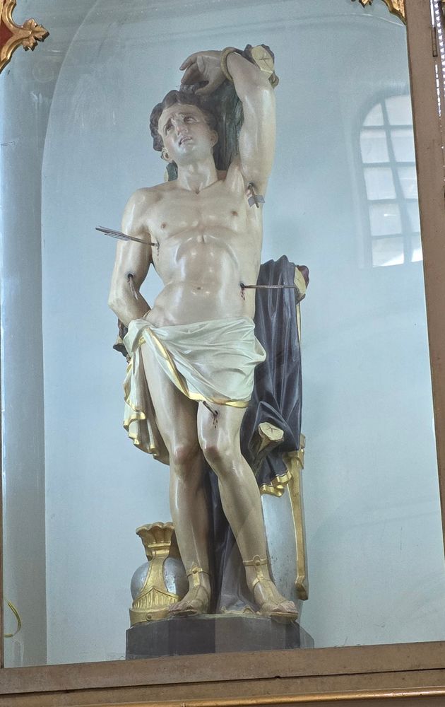 It's a statue of Saint Sebastian, shot with arrows, one of which is in his armpit. He is almost nude and looks like he's having a good time. 