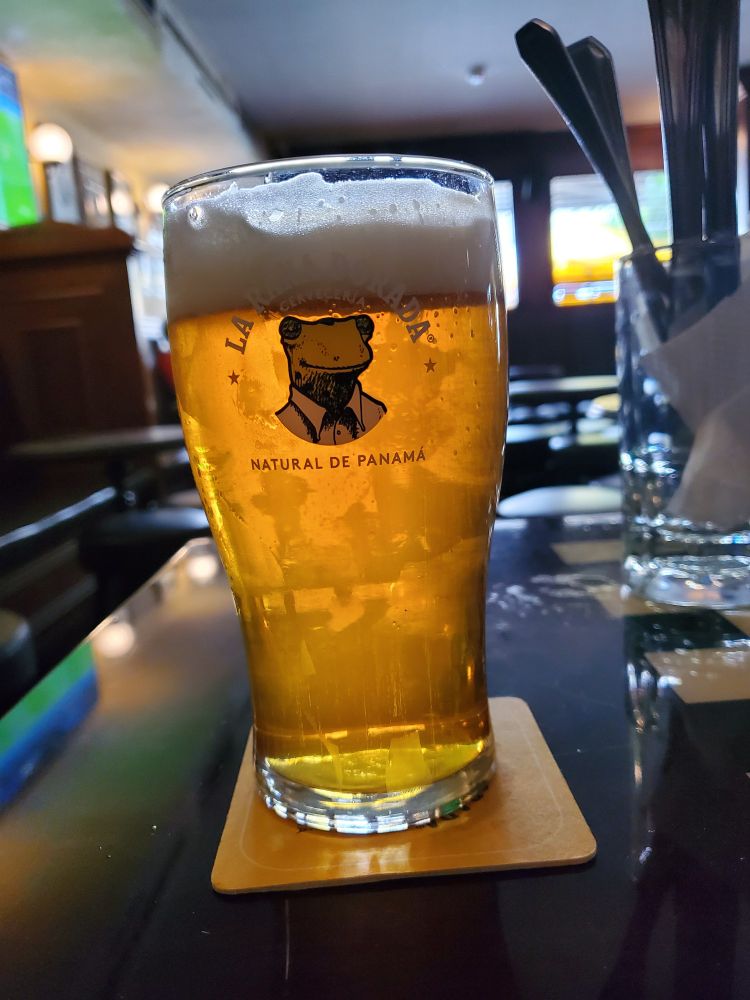 It's an IPA beer in a pint glass with Ka Rana Dorada and frog in a suit logo. Natural de Panamá.