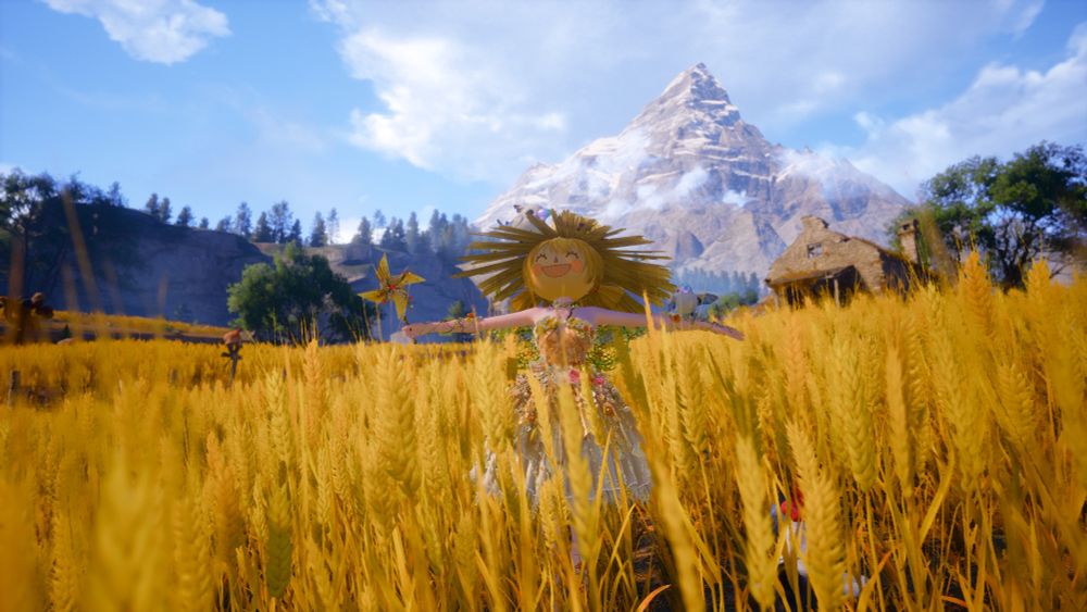 A screenshot from the game Infinity Nikki depicting a woman standing in a golden wheat field and dressed as a scarecrow. The woman gleefully dons a large and round mask with a giant smile on it, shielded by an even larger straw hat. She extends her arms to either side, one wielding a spinning pinwheel and the other balancing a bird. The towering mountains can be seen beyond a forested horizon.