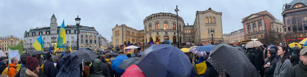 Ukrainske flagg og paraplyer i folkehav foran Stortinget.