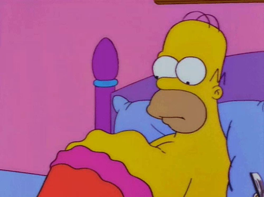 homer simpson laying in a bed with a pink blanket