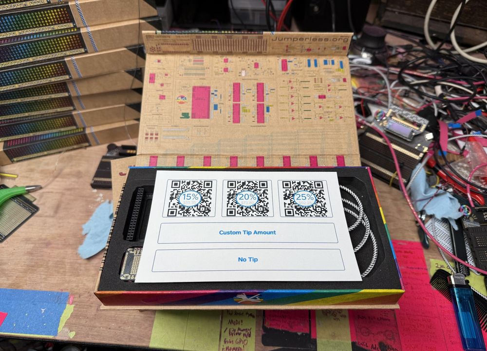 A printed out copy of the "Would you like to leave a tip?" screen from a POS system inside a Jumperless V5 box. With real QR codes.