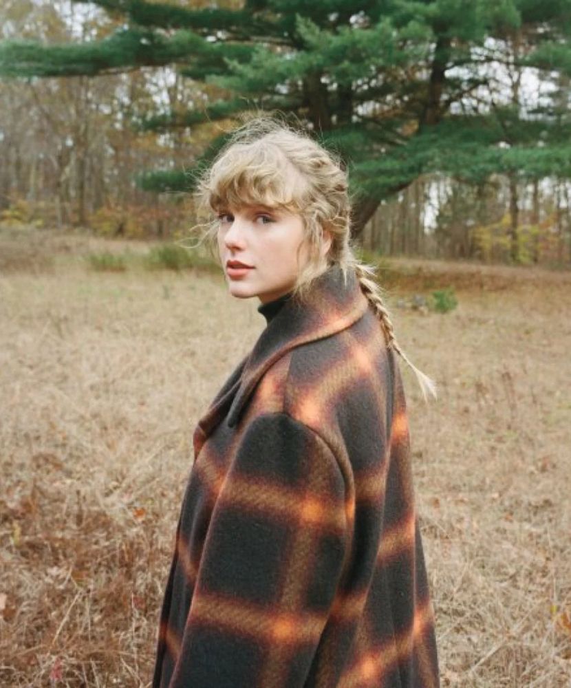 Taylor Swift looking back while wearing the iconic plaid evermore jacket!