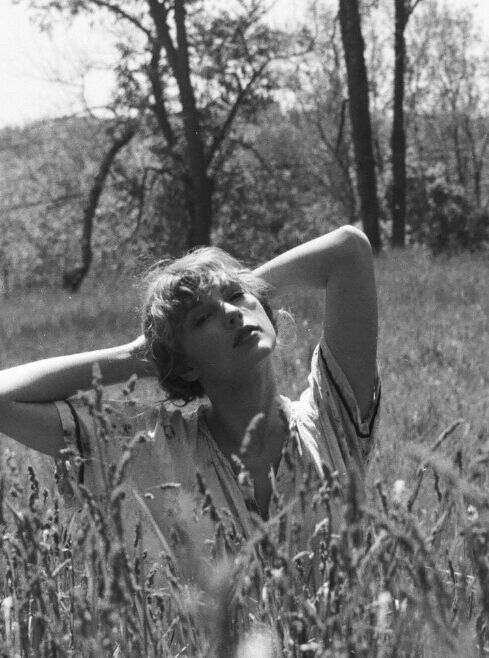 Taylor Swift sitting in a field with her hands behind her head