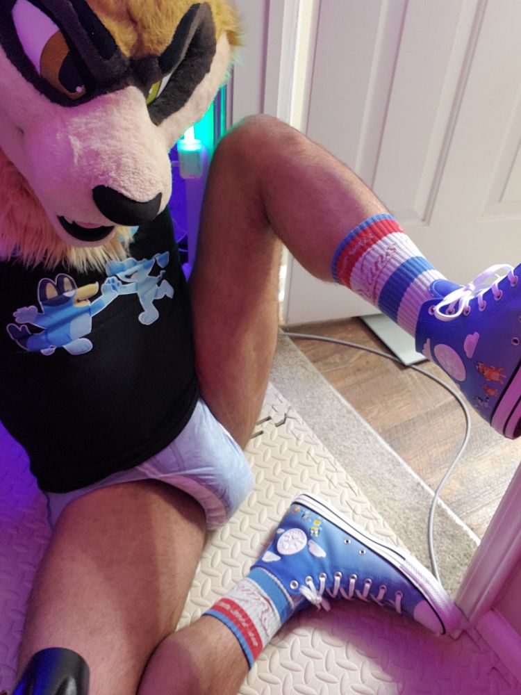 This time the ferret is sitting on the ground with one leg bent on the ground and the other rest against a bathroom doorframe blocking the path in. Shoes and pullup are the focus, and Bluey + Blue shirt from Ramps Inside is more visible