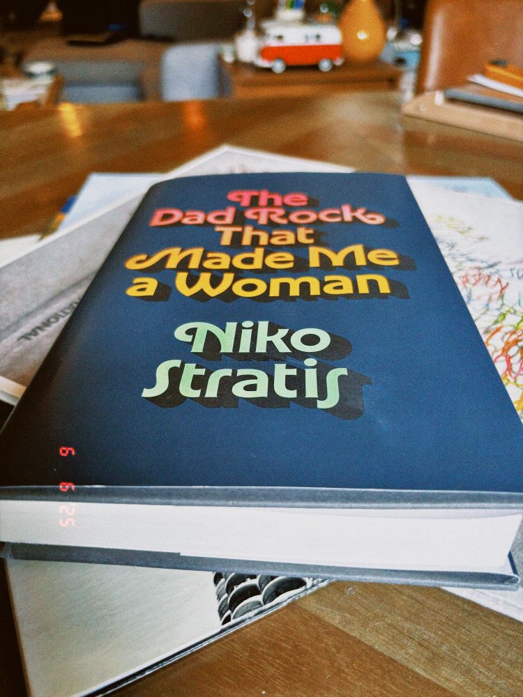 a book with a blue cover, and text that reads the dad rock that made me a woman by niko stratis