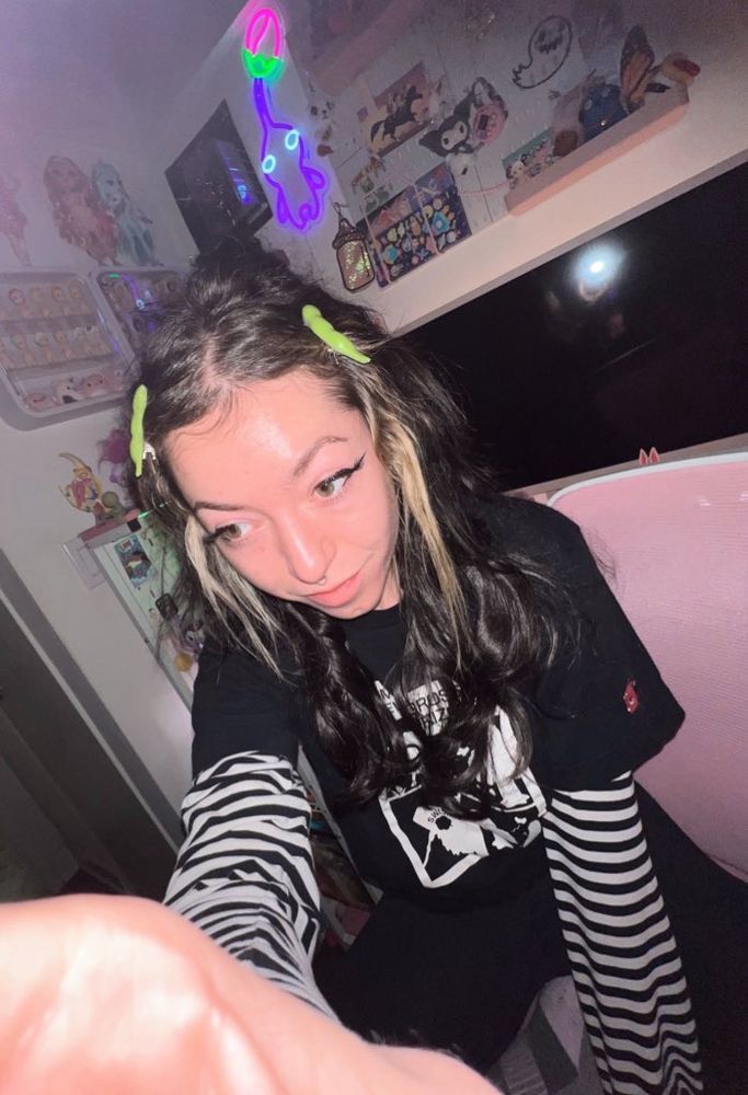 rocket being a goon at her desk wearing edamame hair clips and a striped long sleeve, adorned with an animal crossing tee from uniqlo on top 
