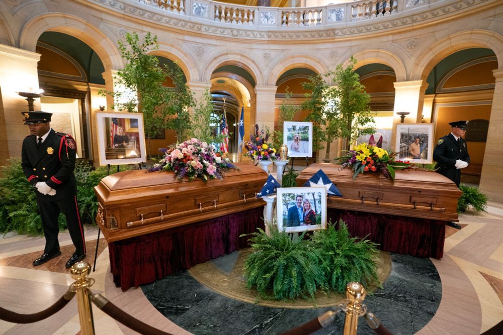 Melissa and Mark Hortman's caskets, and Gilbert's urn in the MN capitol rotunda. Trees dedicated to them surround their caskets. Service members stand guard.