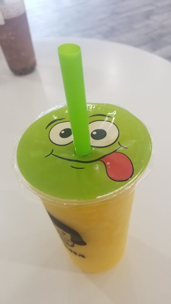 Image of a cup with a plastic lid that has a cute smiling face sticking it's tongue out.
There is a straw going right thru where the nose is supposed to be.