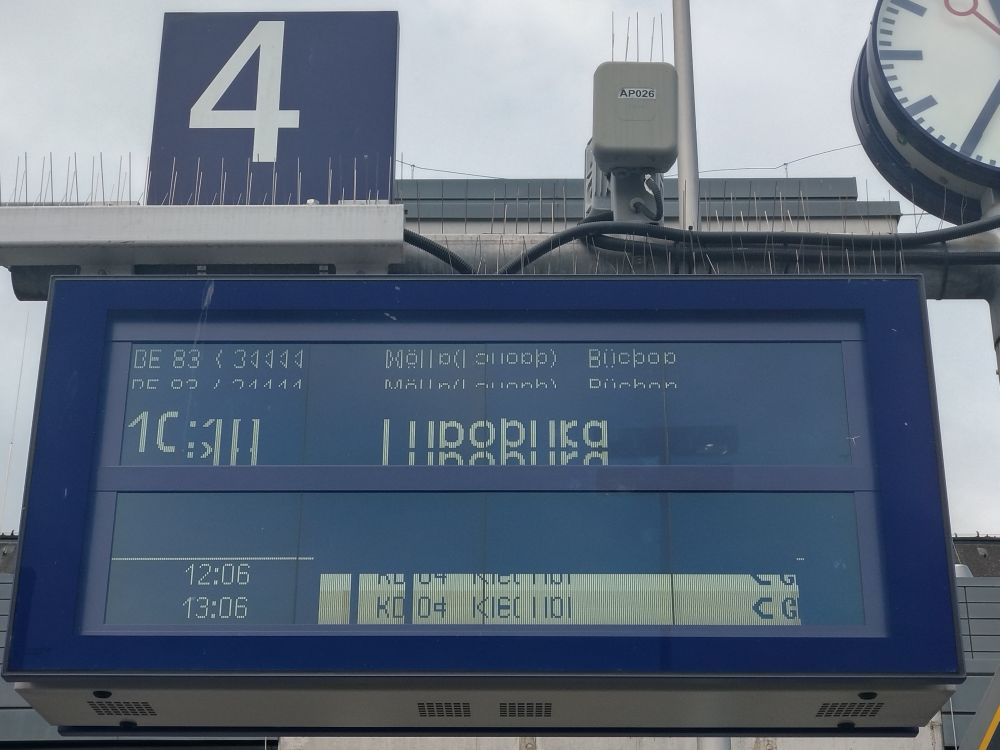 Eine Bahngleisanzeige mit Bildfehler zeigt kryptische Lettern