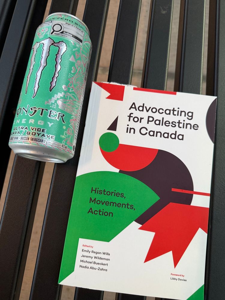 A book (Advocating For Palestine In Canada) sits on a train station bench beside a can of monster.