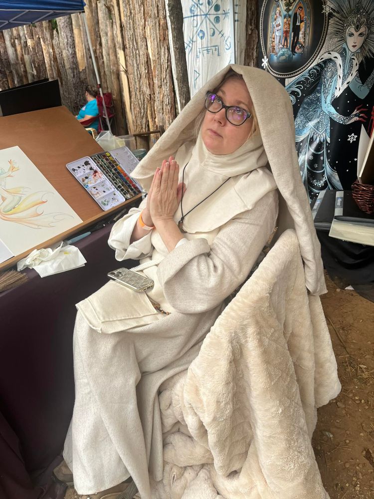 A woman with her face raised in prayer, dressed in all white nun's robes.
