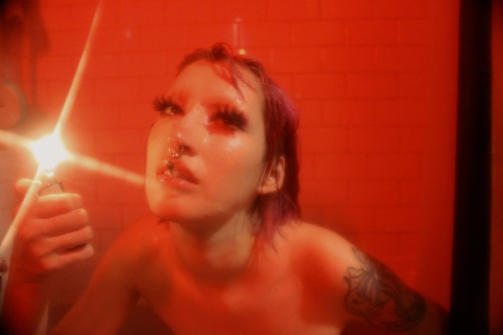 Portrait of me in a red lit room with a joint in my mouth and flicking a lighter 