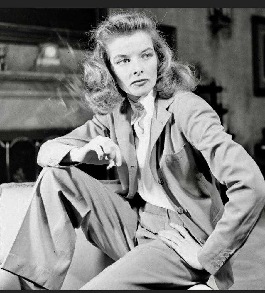 Katharine Hepburn sitting smoking a cigarette in a suit