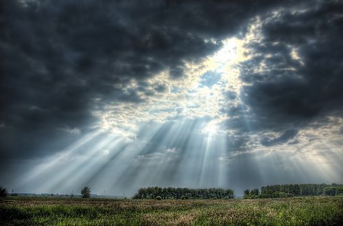 Picture of the sun breaking through stormclouds over a field