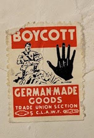 Label affixed to the back of an envelope. Issued by the Trade Union Section C.L.A.W.F. [i.e. Canadian League Against War and Fascism], it features a caricature of Hitler marching over dead bodies with a hand stopping him and the slogan "BOYCOTT GERMAN-MADE GOODS"