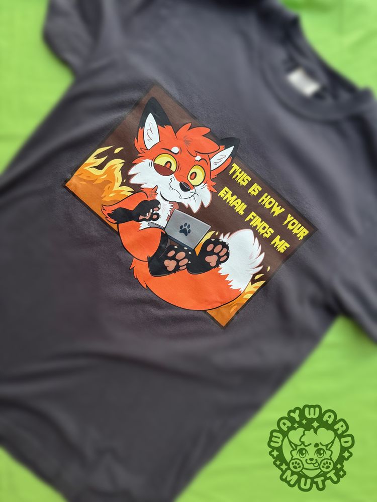 a dark grey shirt with a fox on a laptop with fire behind them, text reads "this is how your email finds me" 