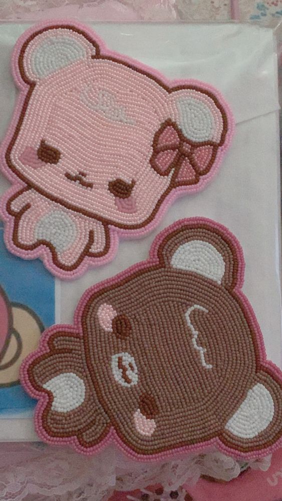 Photo of two matching teddy bears made with beads sewn on felt. One bear is pastel pink with pink blush cheeks and a pink bow as well as white round belly and inner ears; the other bear is brown with pink blush cheeks and white belly and inner ears. The bears are on top of a pink and white lace album with a sheet of felt and printed paper underneath them.
