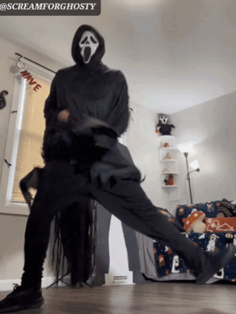 a person in a scream mask is dancing in front of a window