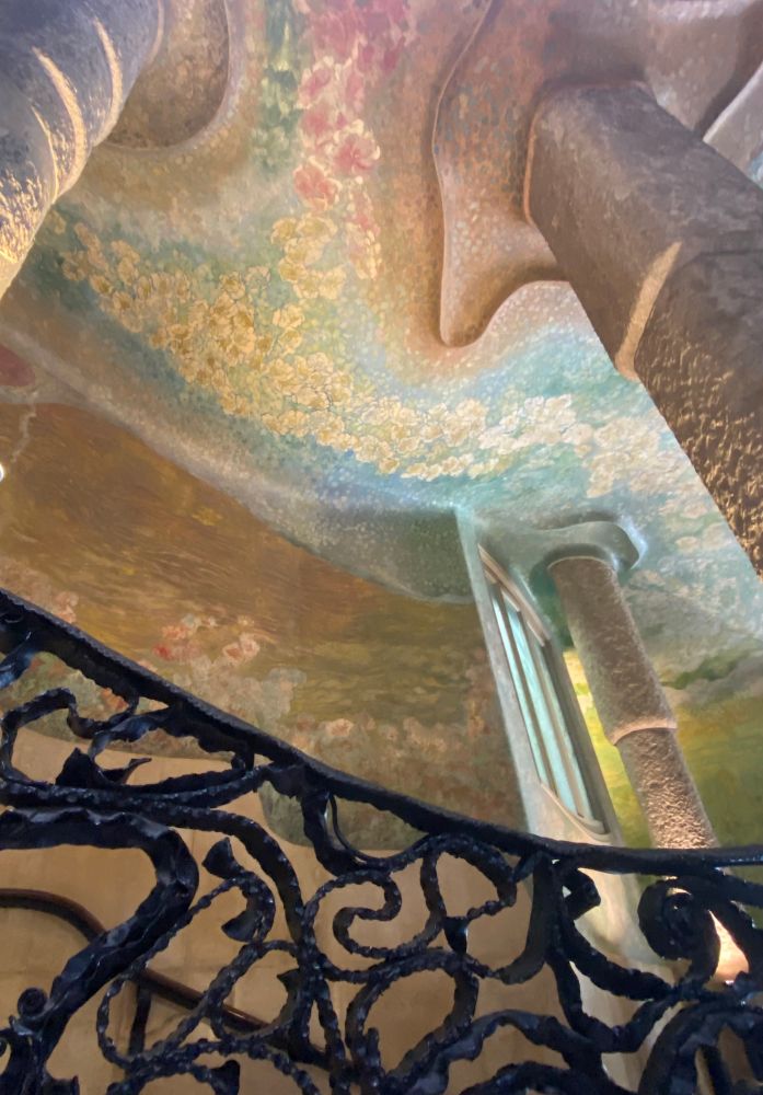 Photo of the inside of Gaudi’s La Pedera building with decorative railings and mosaic painted walls