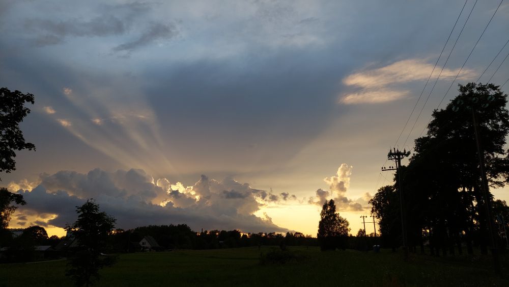 Landscape shot of a sunset behind clouds, there's some rays coming through.