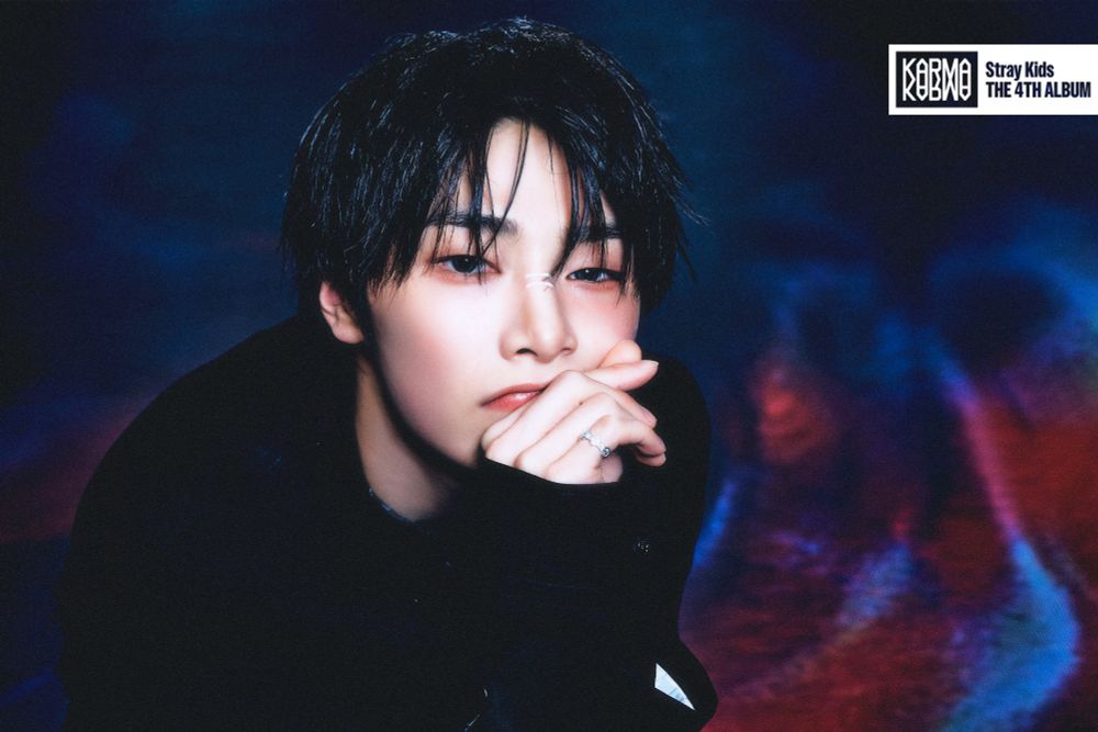 Jeongin for Karma, looking sooo beautiful. He has white stripes over his nose and he's also looking at the camera, hand in front of his chin.