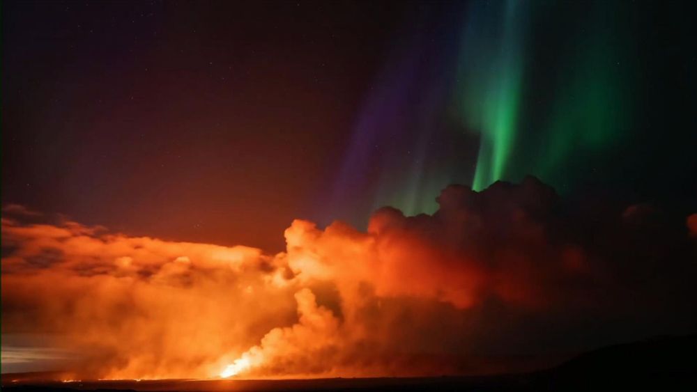 Northern lights shine above erupting volcano in Iceland