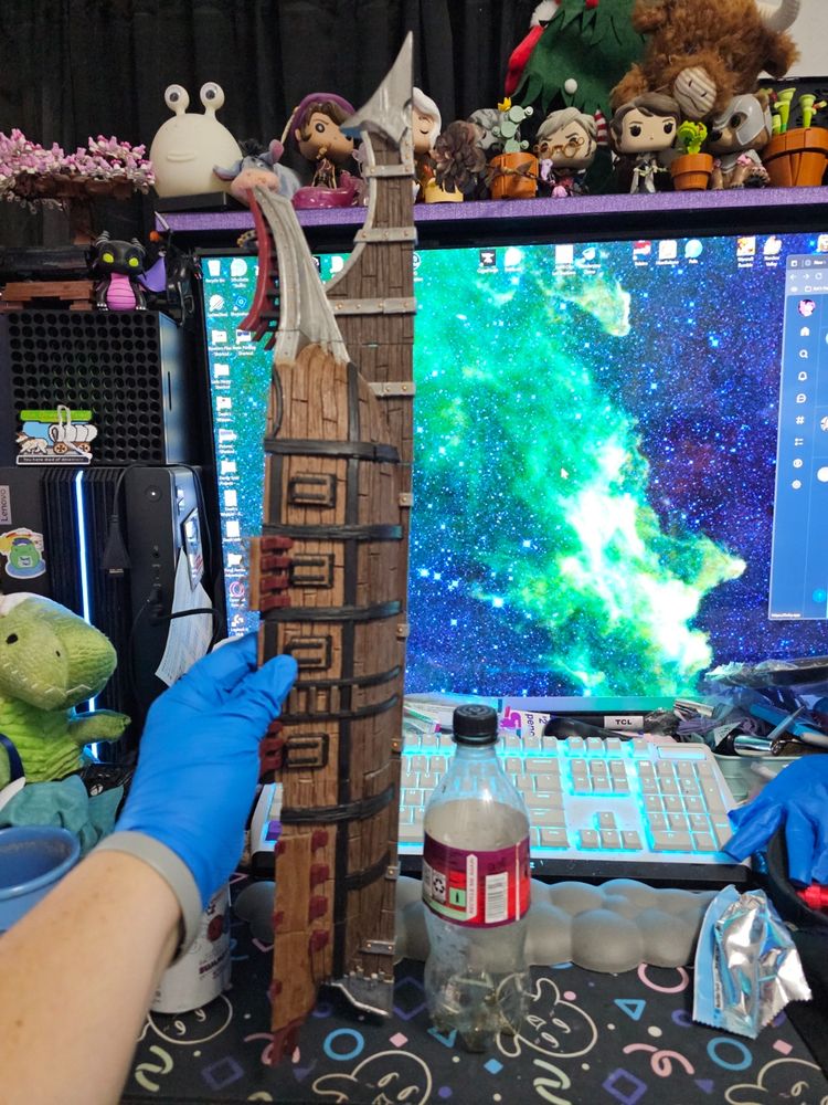 Photo of a hand holding the full bottom of a ship.  The ship is next to a 20-oz bottle.  This is in front of a 43-inch monitor