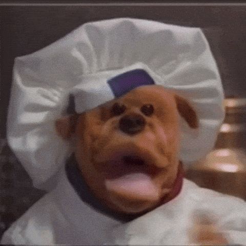 a puppet dog wearing a chef 's hat and a white coat