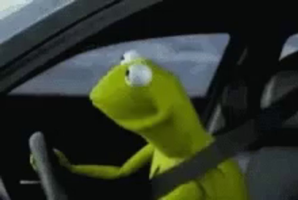 kermit the frog is driving a car with a seat belt around his neck .