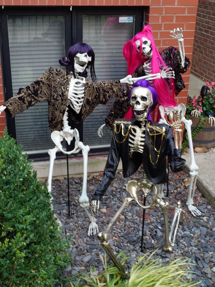 skeletons dressed as the girls from K-pop Demon Hunters. Rumi is a gold skeleton