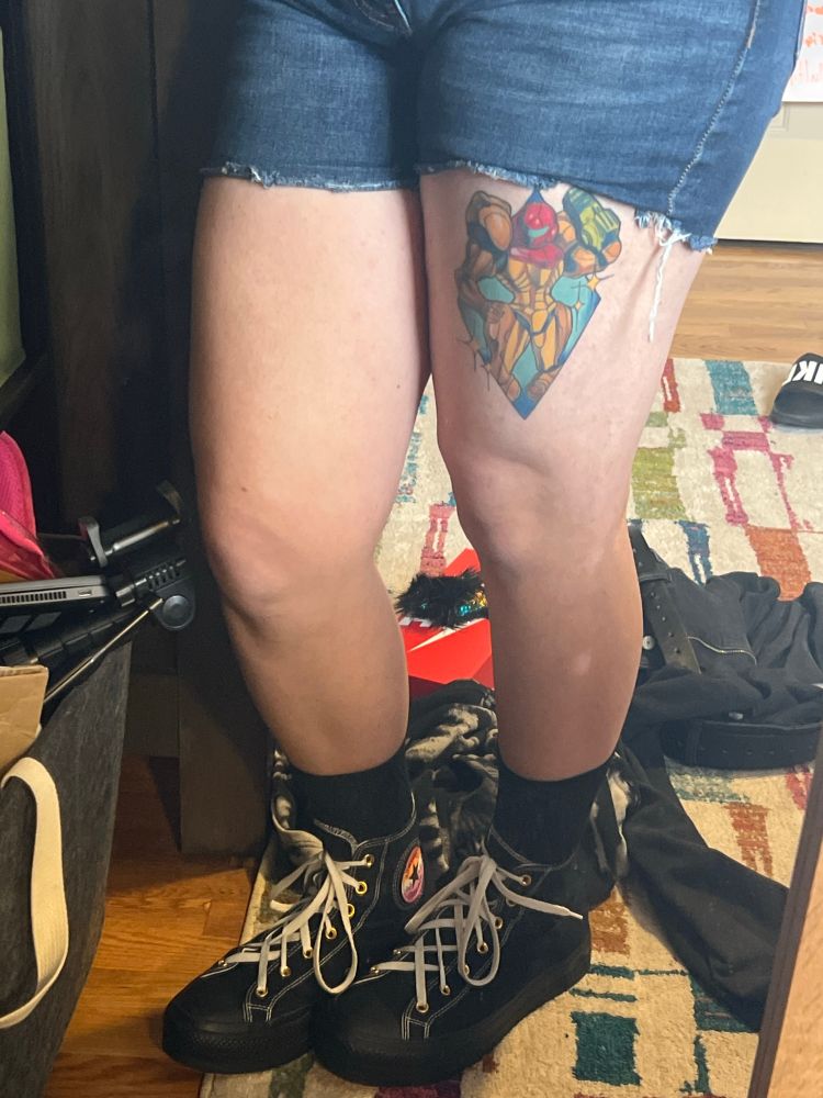 my legs in denim shorts. you can see my tattoo of Samus Aran on my thigh and I’m wearing black high top converse. legs are incredibly smooth. 