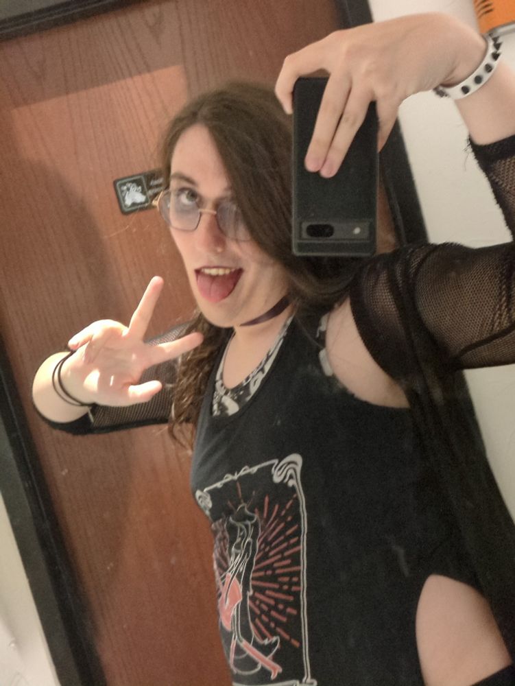 Alt/punky/goth trans girl taking a selfie in a silly pose