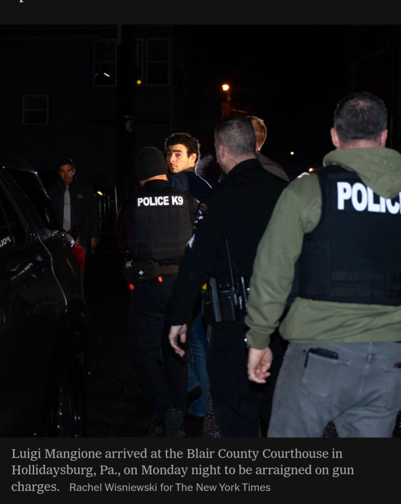 Luigi Mangioni looking back at the camera, the only visible face, dramatically lit