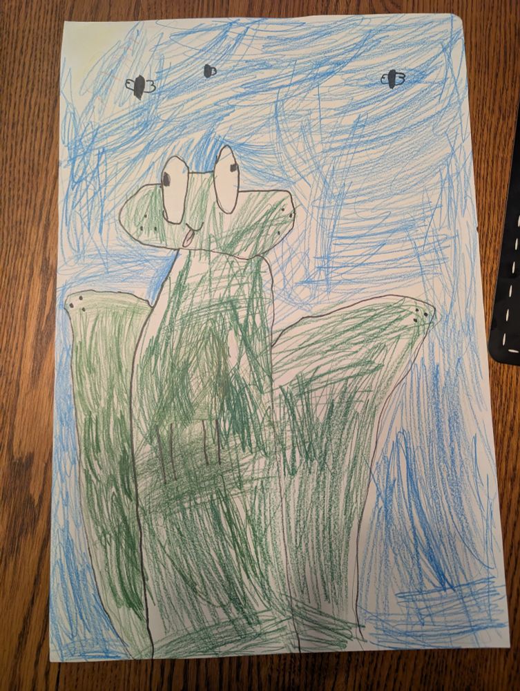 A child's drawing of a frog. His eyes are pointing in opposite directions, his tongue is sticking out, and he has freckles.