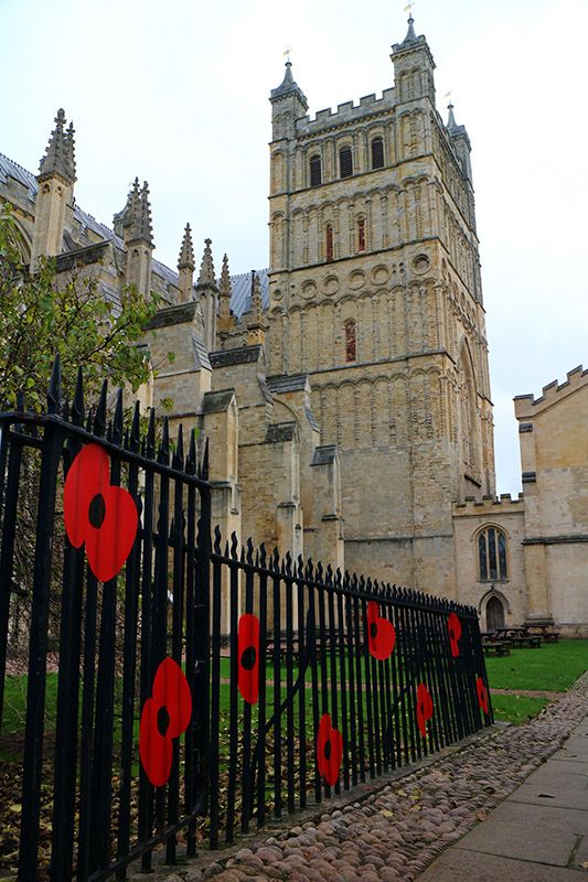 Symbolic poppy flowers on a railing with Exeter Cathedral beyond.