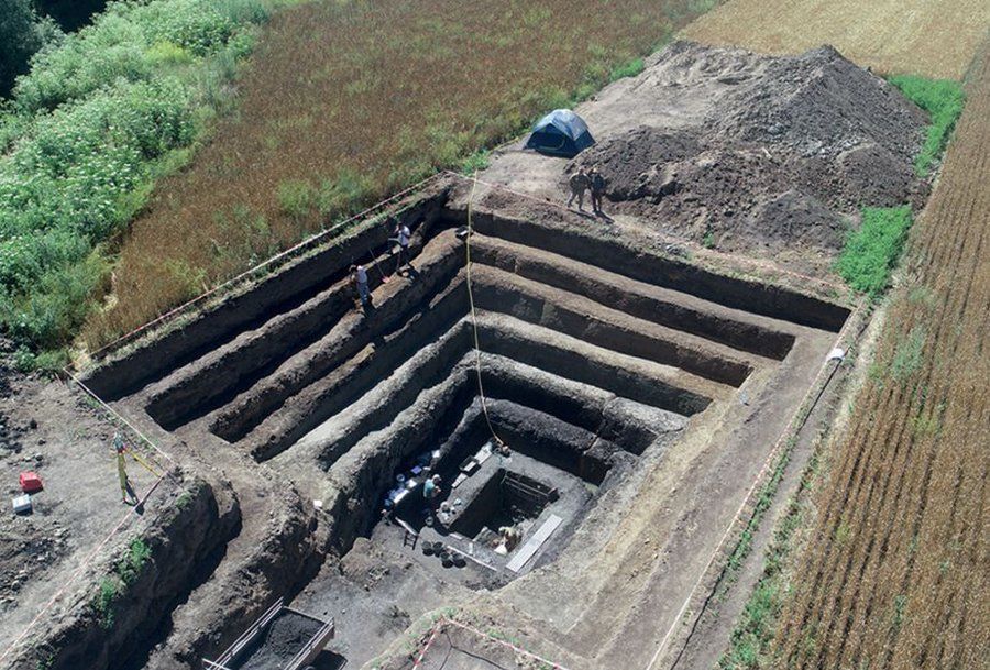 Oblique aerial view of a square, tiered excavation.