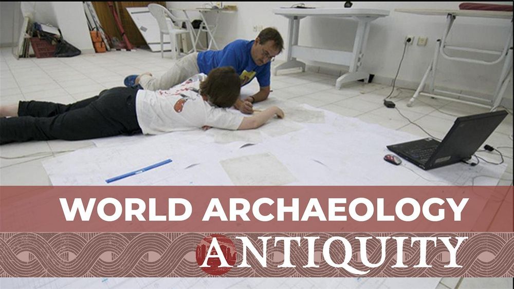 Two researchers lying amongst papers on the floor, discussing the diagrams drawn on them, with the text 'World Archaeology, Antiquity'. 