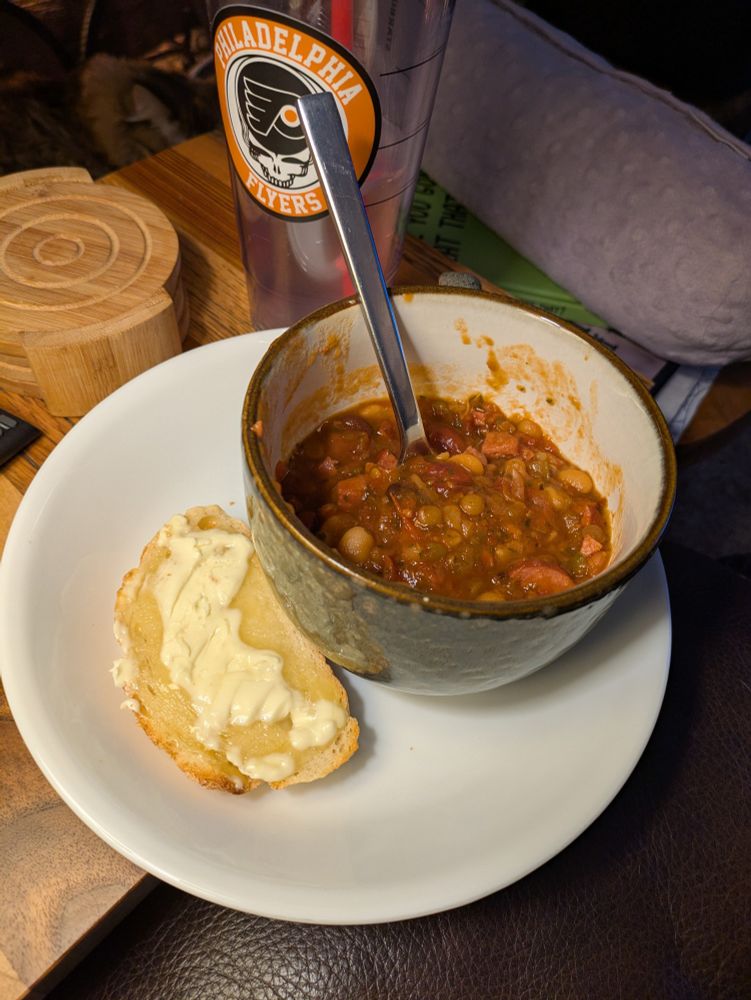 A large mug of kielbasa and multi-bean soup with buttered sourdough. 