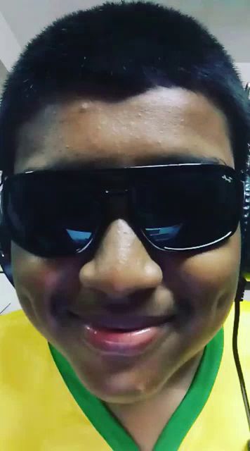 a boy wearing sunglasses and a yellow and green shirt smiles